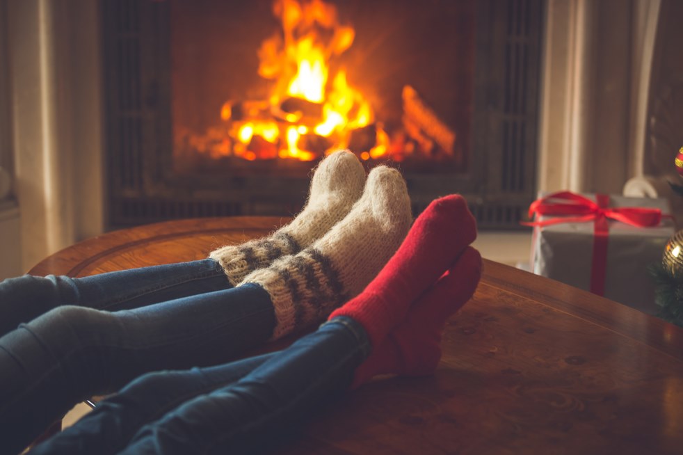 Two people warming their feet by the fire.